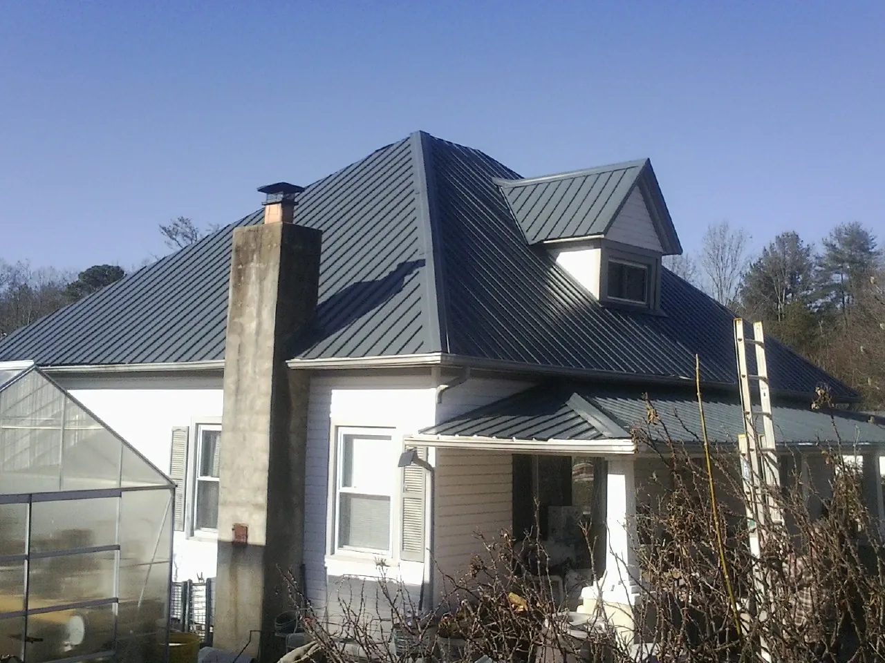 Dark blue standing seam metal roof on a white farmhouse with dormer — Slate & Tile Roof Repair by Roofing Brothers in Folsom