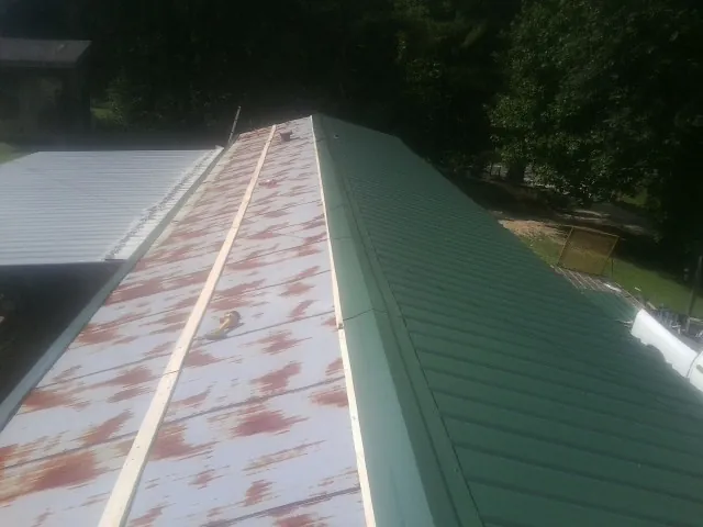 Old rusted panels beside newly installed green metal roofing — Wind Damage Roof Repair by Roofing Brothers in Folsom