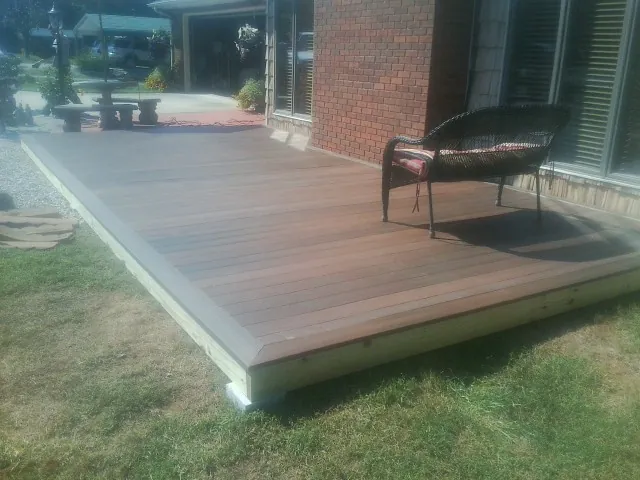 New wood deck and wicker chair beside a brick house in Folsom