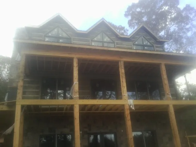 Dormers and porch framing on a large log home under construction — Roof Coating work by our crew in Folsom
