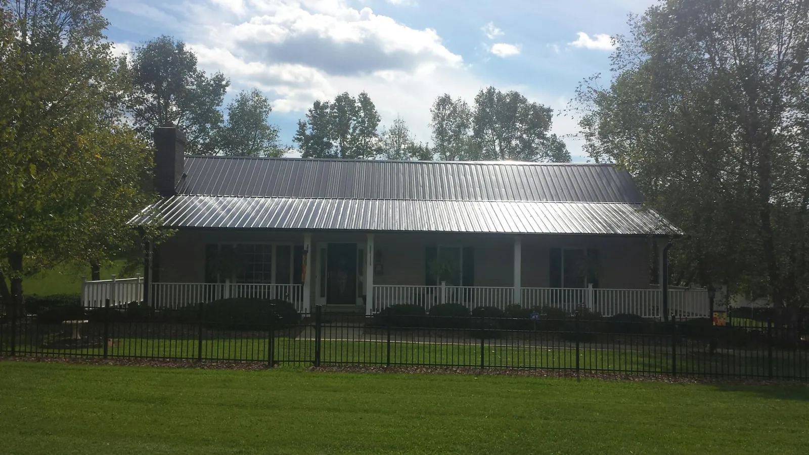 Gray metal roof on a brick ranch with a full width front porch — Gutter Guard Installation work by our crew in Folsom